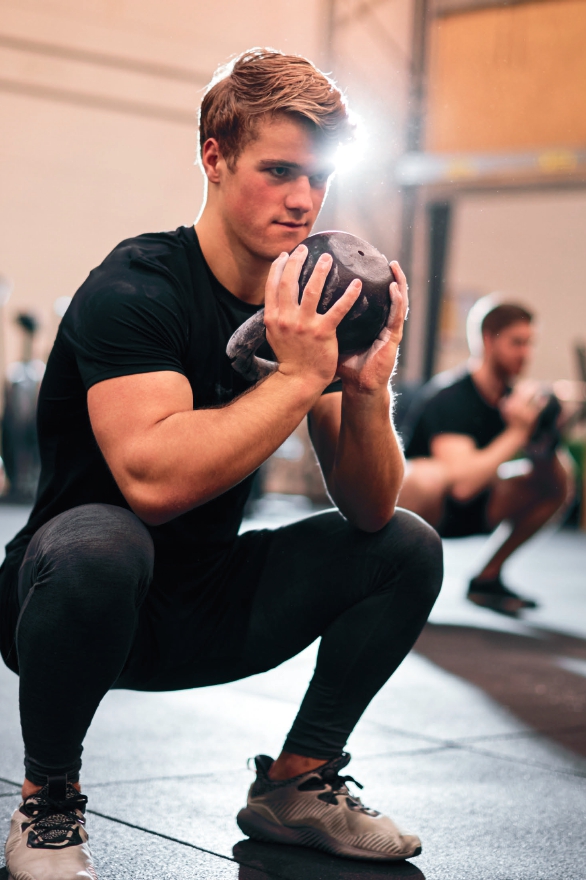 Homme faisant un squat avec un ballon de 4 kilo
